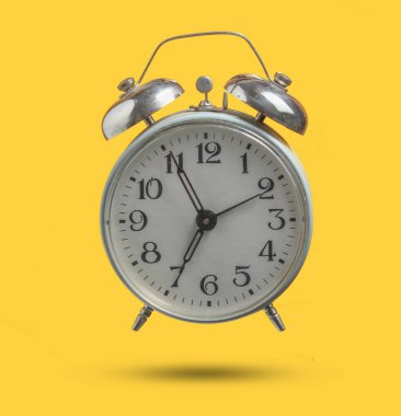 Eski retro tarzı çalar saat sarı arka plan üzerinde izole. Sabah 6:55'te. Minimalizm. Gölgeli fotoğraf