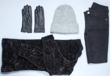 Velor siyah kazak, kot pantolon, deri eldiven, gri bir arka plan üzerinde sıcak yün şapka. Üst te. Düz döşeme stili