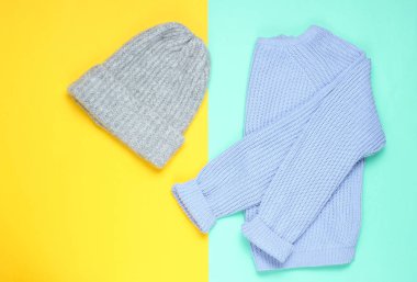 Kışın yün şapka, renkli bir arka planda süveter, minimalizm, üst manzara, düz stil.