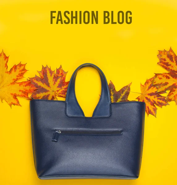 Autumn collection. Fashion blog. Leather bag of fallen autumn leaves on a yellow background. Seasonal accessories. Top view. Copy spac