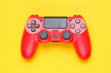 Sarı arka planda modern kırmızı gamepad (joystick). Top vie