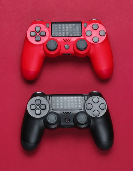 赤い紙の背景に2つのゲームパッド ビデオゲームミニマリズム トップビュー — ストック写真