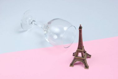 İmparatorluk kulesi heykelciği, gri-pembe kağıt backgroun üzerinde boş şarap bardağı