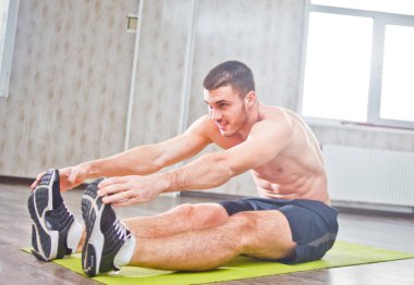 Yoga çalışmasından önce bacaklarını açan genç bir adam.