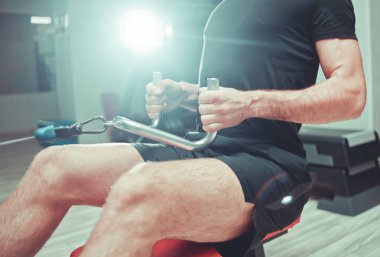 Adam otururken kolları çekerek ekipman kürek eğitim makinesi ile eğitim olduğunu. Spor salonunda ağırlık ile sırt kasları egzersiz.