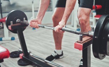 Bir adamın elinin parçası. Adam spor salonunda tren pazı için raftan çıtayı yükseltir. 