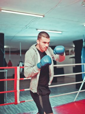 Erkek boksör spor salonunda boks halkaiçinde gölge boks yapıyor. Boksör bir boks studi yaptığı yumruklar pratik