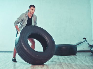 Young sports man raises a large weight wheel. training process. Functional trainin