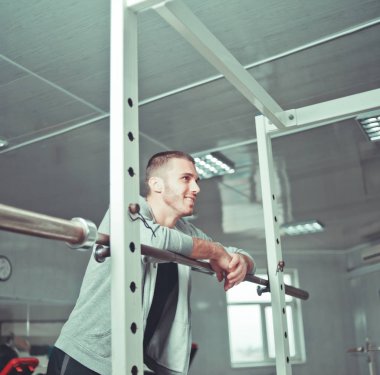 yakışıklı erkek atlet spor salonunda eğitim dinlenme ve gülümseyerek ve düz görünümlü