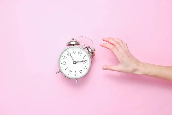 Vrouwelijke Hand Neemt Wekker Roze Achtergrond Bovenaanzicht Tijd Wakker Worden — Stockfoto