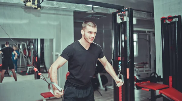 handsome sporty man works out pushing up excercise in crossover training machine at gym