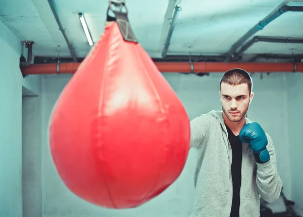 Bonito Boxeador Concentrado Masculino Treina Socos Mão Com Saco Perfuração — Fotografia de Stock