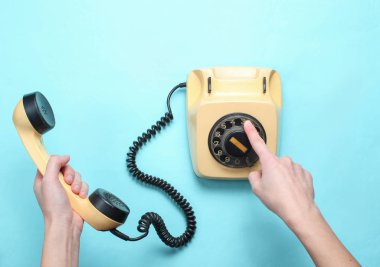 Kadın elleri döner telefonun numarasını alır ve mavi pastel arka plan üzerinde yakışıklı tutar. Üst görünüm, minimalizm