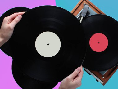 Vinil plak tutan kadın elleri, iki renkli arka plan üzerinde plakları olan vinil oynatıcı. Retro tarzı, 80s, üst görünüm