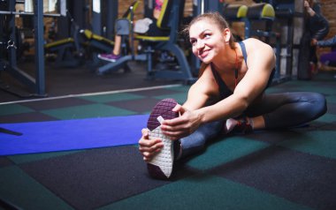 Spor salonunda sağ bacağını esneten genç bir kadın.