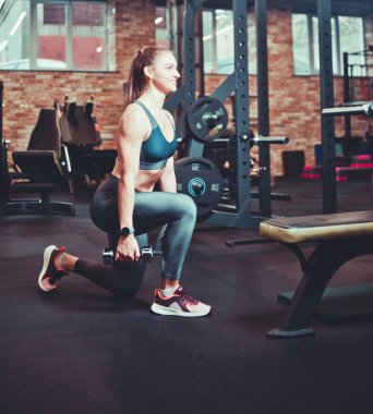Modern Gy içinde dumbbells ile lunges yapıyor atletik Smilling kadın