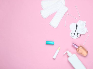 Pembe pastel arka plan üzerinde alan kadın güzellik ve hijyen ürünleri kopyalayın. Parfüm şişesi, hijyenik ruj, pedler, şişe kremi, tırnak makası. Düz yatıyordu stil