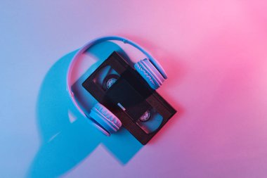 Kulaklıklı video kaset. Retro dalga, kırmızı mavi ışık, ultraviyole. Üst görünüm, minimalizm