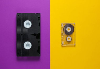 Pop kültür medyası 80'li. Ses bandı, mor-sarı arka plandaki video kaset. Üstte görüntü