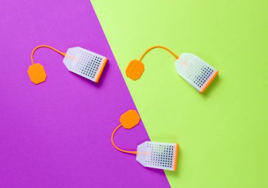 Renkli arka planda üç silikon çay poşeti. Üst görünüm, minimalizm