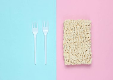 Ham anlık erişte ve plastik çatal bir pastel arka plan, minimalizm, üstten görünüm