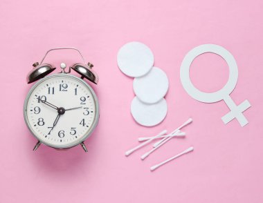 Öz bakım zamanı. Hijyen ürünleri, kadın cinsiyet sembolü, pembe pastel arka plan retro çalar saat. Üst te. Düz yatıyordu