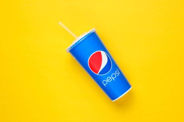 Ukrayna, Odessa-7 Ocak 2019: Sarı arka planda saman bulunan Pepsi kağıt bardak. Üst Manzara. Minimalizm