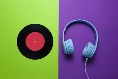 Retro tarzı. 80s. Vinil kayıt, yeşil-mor arka plan üzerinde kulaklık. Üst te. Minimalizm