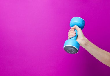 Kadın el pembe arka plan üzerinde mavi plastik halter tutun. Kopyalama alanı