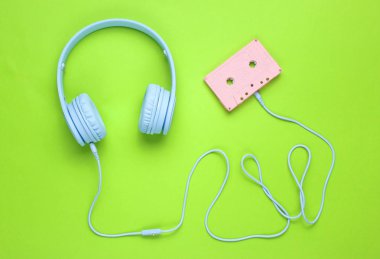 Yeşil arka plan üzerinde ses kaseti kablo ile mavi kulaklıklar. Minimalizm. Üstte görüntü