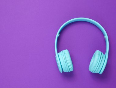 Mor arka planda modern kablosuz mavi kulaklıklar. Üst Manzara. Boşluğu kopyala