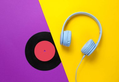 Retro tarzı. Müzik aşığı. Kulaklıklar, mor sarı arka planda lp kaydı. Düz yatıyordu. Üstte görüntü.