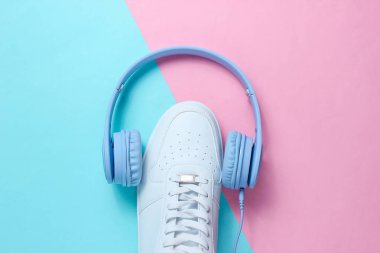 Minimalizm. Müzik aşığı. Kulaklıklar, mavi renkli beyaz spor ayakkabılar. Üst Manzara. Düz yatıyordu