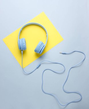 Sarı-gri yaratıcı arka planda kablolu mavi kulaklıklar. Minimalizm. Üstte görüntü