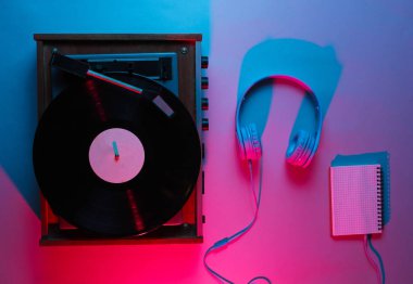 İp kaydı ve kulaklığı olan vinil çalar. Gece kulübü. Retro dalga, kırmızı mavi ışık, ultraviyole. Üst görünüm, minimalizm