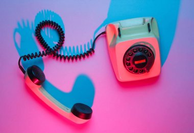 Eski model döner telefon. Retro dalga, pembe mavi neon ışık, morötesi. Üst görünüm, minimalizm