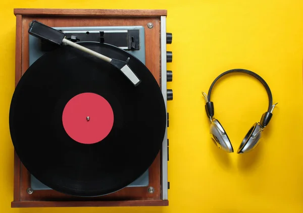 Retro vinyl record player, headphones on yellow background. Top view