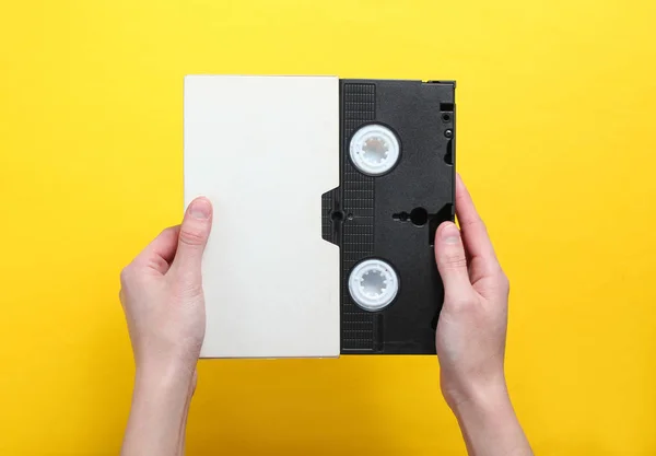 Kobieta Ręce Trzyma Videocassette Pokrywie Kasety Wideo Żółtym Tle Widok — Zdjęcie stockowe
