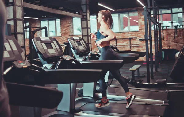 Young sports woman doing cardio training on treadmill. Running on treadmill at gym.