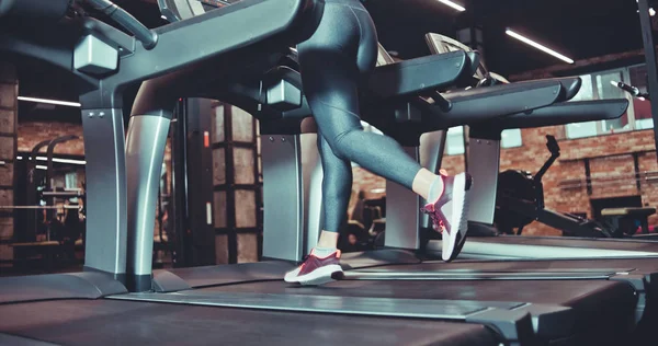 ジムでトレッドミルを走るスニーカーやレギンスの女性の筋肉足 心臓トレーニング — ストック写真