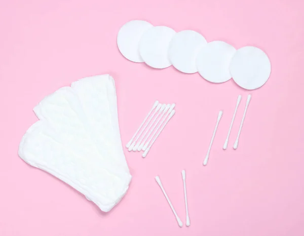 Hygiene products on a pink pastel background. Cotton pads, women\'s pads, cotton ear sticks. Top view, flat la