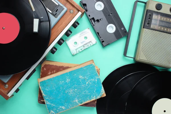 Retro öznitelikleri, 80'lerin medyası. Vinil çalar, video kasetleri, ses kasetleri, kayıtlar, radyo, mavi arka plan üzerine eski kitaplar. Üstte görüntü
