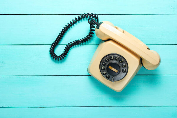 Ретро вращающийся телефон на синем деревянном столе. Атрибуты поп-культуры, вид сверху
.
