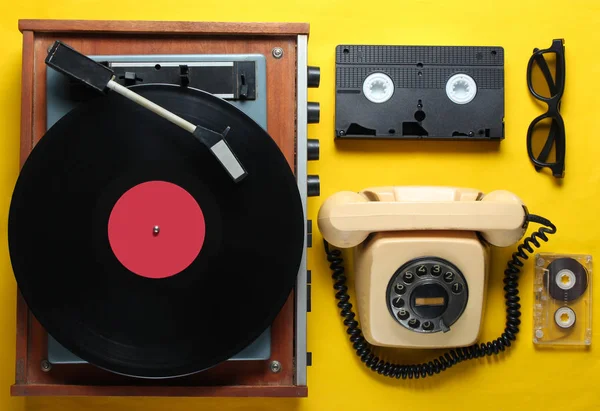 黄色の背景に古風なオブジェクト レトロなスタイル 80年代 ポップカルチャー トップビュー ビニールプレーヤー 回転電話 ビデオ オーディオテープ — ストック写真