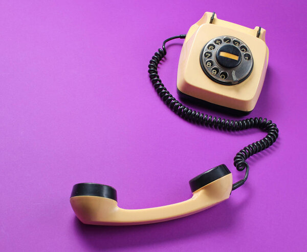 Ретро ротационный телефон с телефоном на фиолетовом фоне
