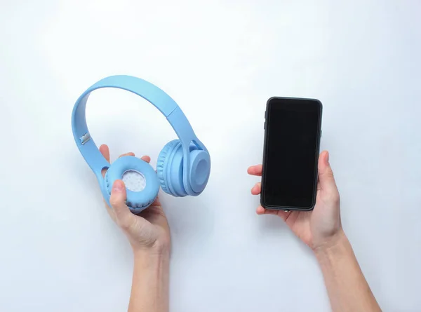 Manos Femeninas Sosteniendo Teléfonos Inteligentes Modernos Auriculares Sobre Fondo Gris —  Fotos de Stock
