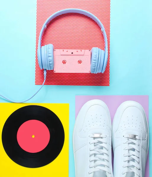 Pop Culture, retro 80s old fashioned objects on a creative background. White sneakers, headphones with audio cassette, lp record. Top view. Flat lay.