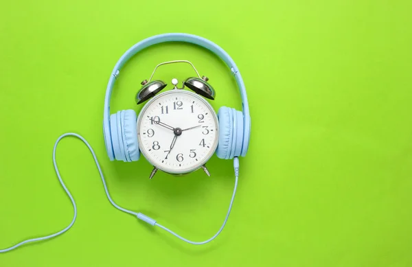 Yeşil arka planda kablolu kulaklıkları olan geri alarm saati. Üst görünüm