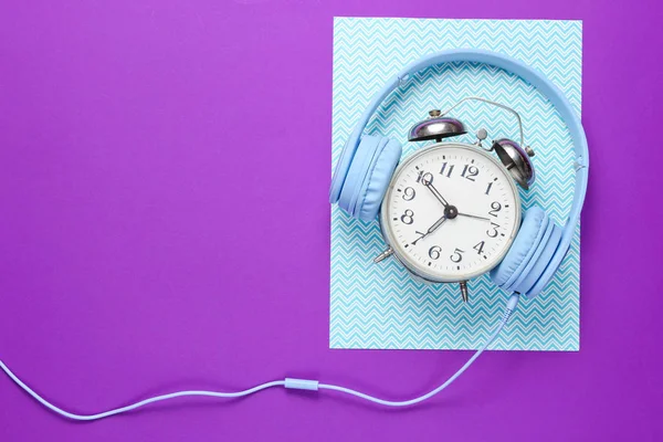 时间听音乐的概念 复古闹钟与有线耳机在紫色蓝色创意背景 顶部视图 — 图库照片
