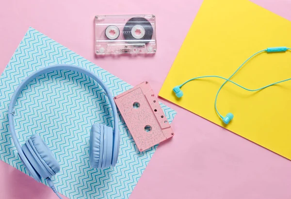 Headphones and earphones with audio cassettes on colored paper backgrounds. Retro style, minimalism. Flat lay. Top view.